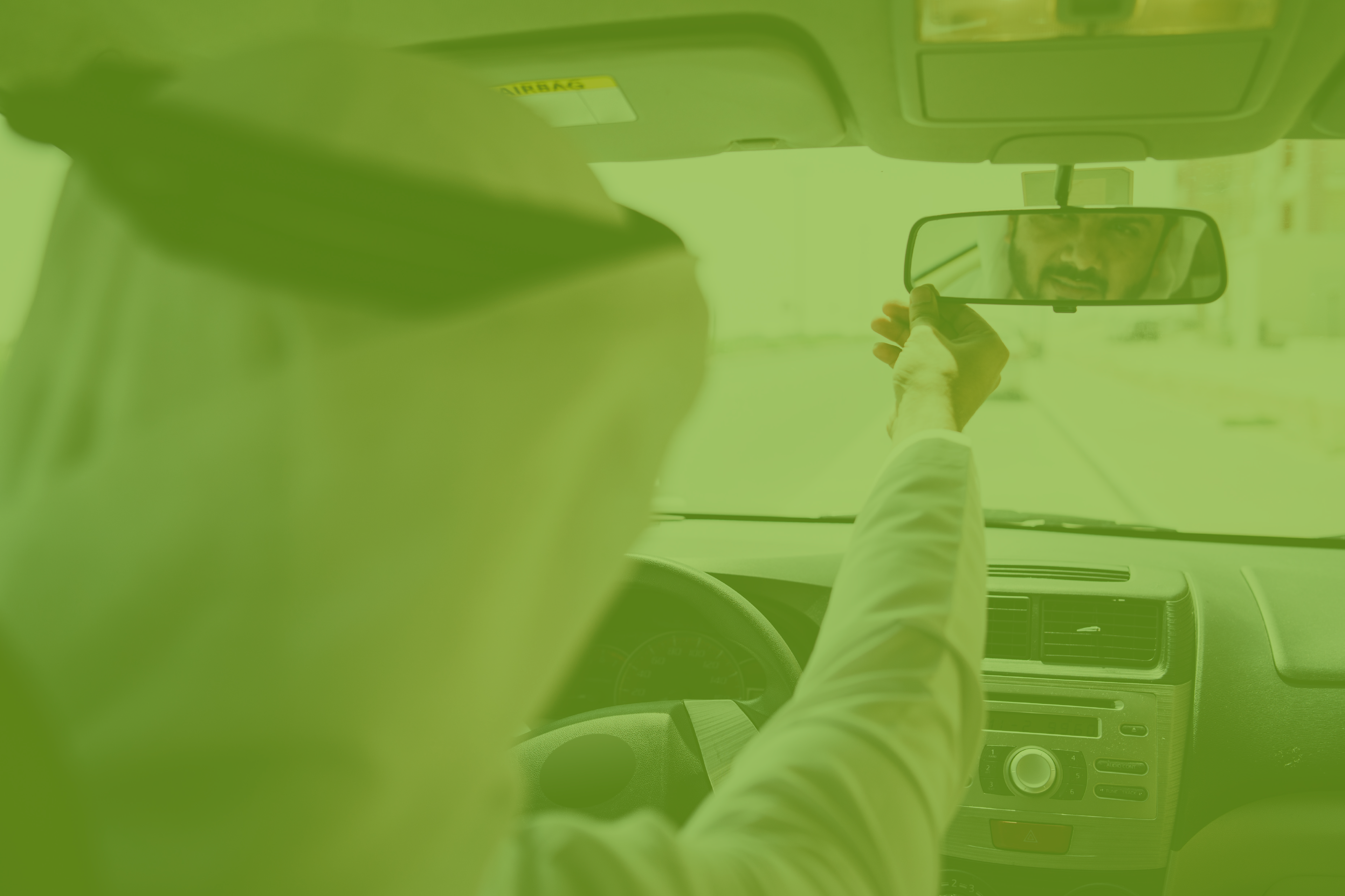 a man driving a car looking at the rear-view mirror in order to strategize his movement 